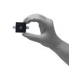 Gloved hand holding small black electronic sensor component